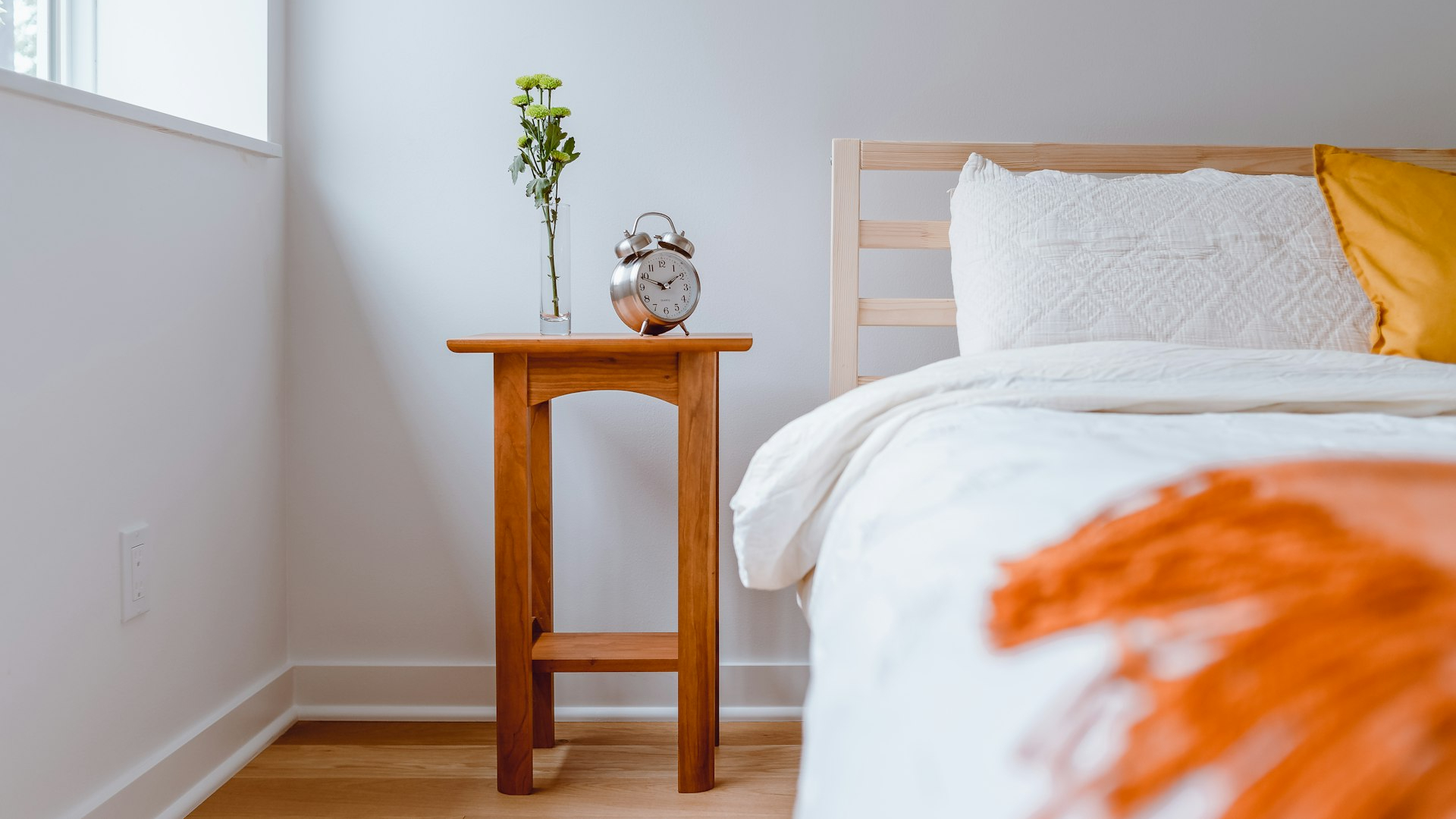 brown wooden table with white and orange floral bed linen